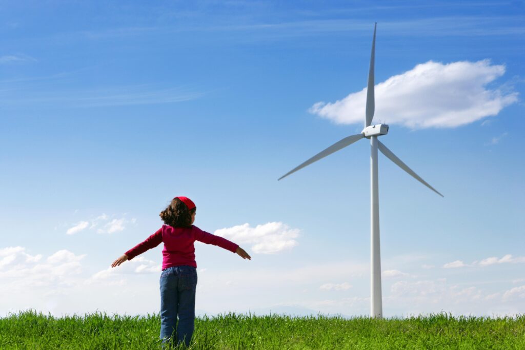 young girl standing in front of wind turbine