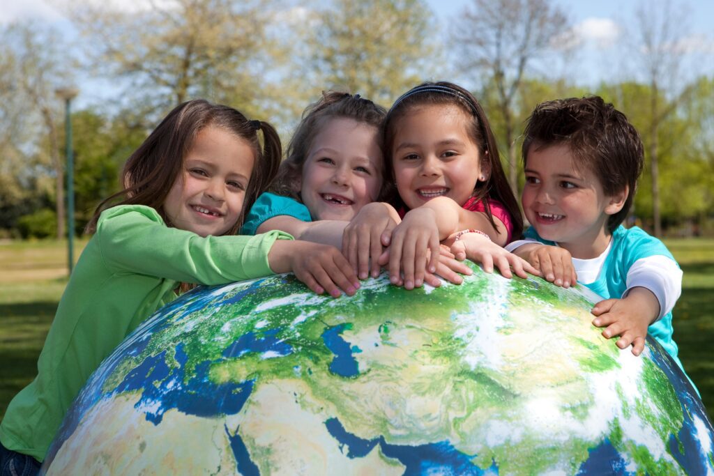 four children hugging giant Earth ball