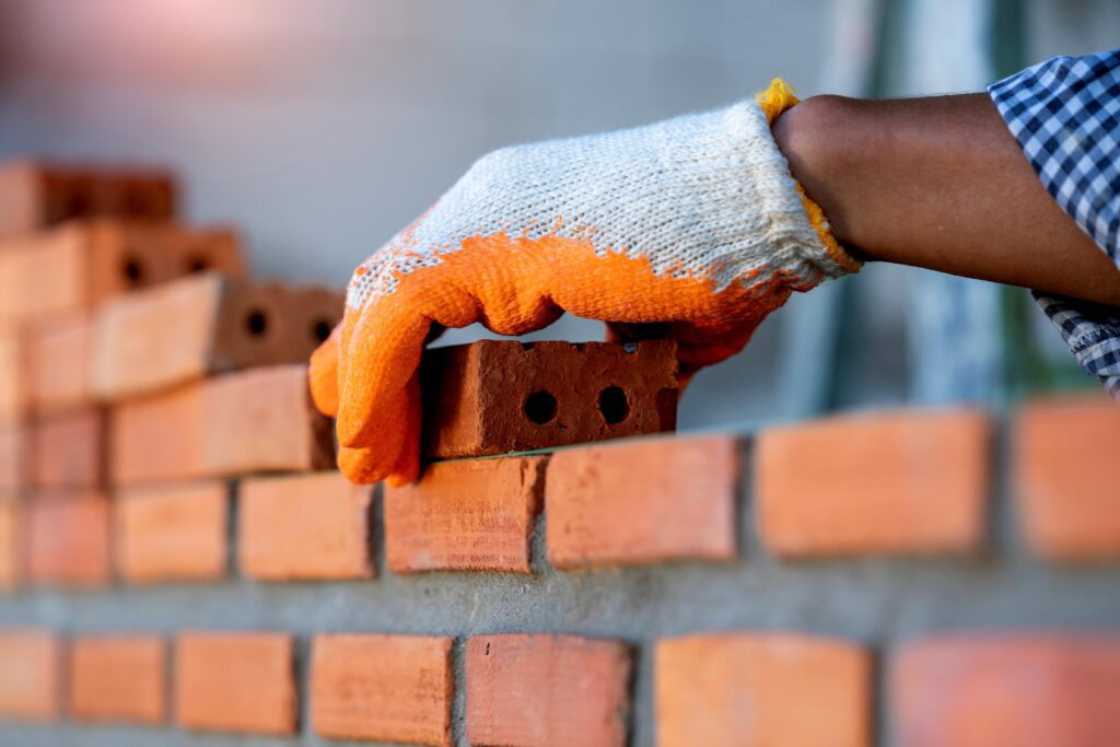 hand placing brick on wall