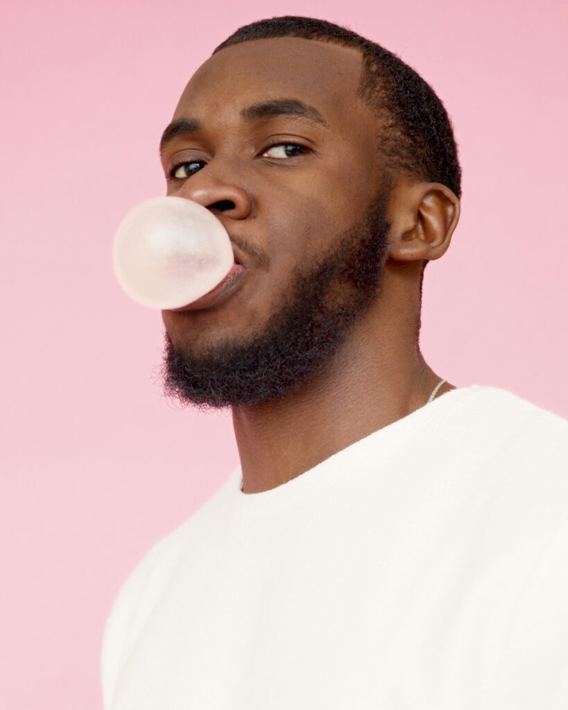 man chewing gum on pink background